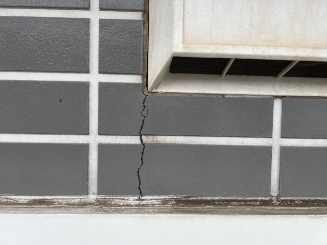 外壁タイルに走る大きなひび割れと通気口まわりの汚れ